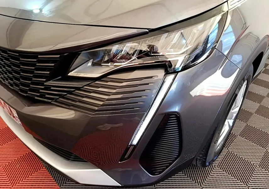 Gros plan sur l’avant droit gris clair du Peugeot 5008 2021 avec phares LED et calandre noire distinctive.