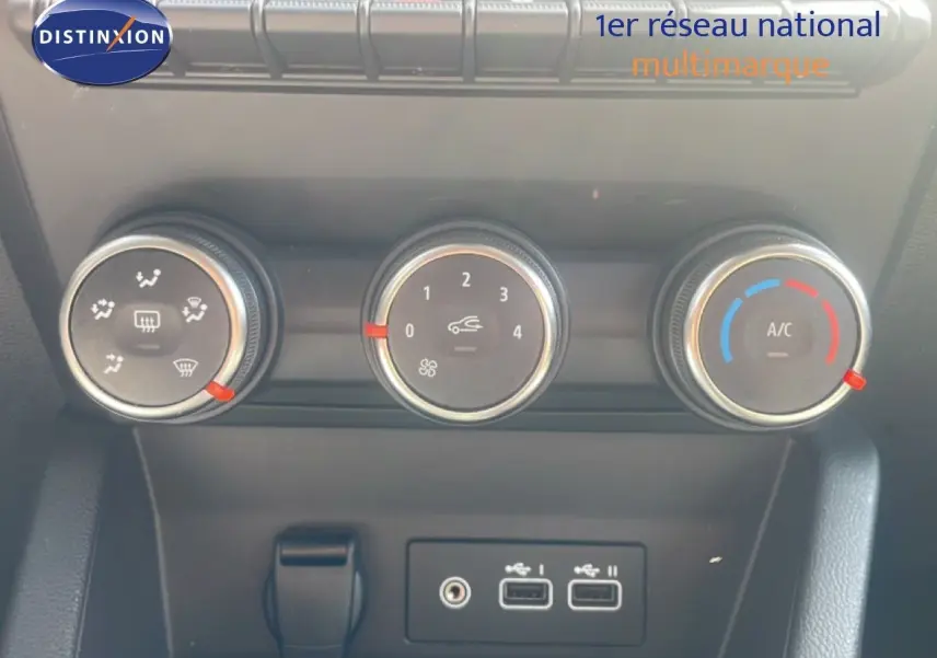 Gros plan sur les commandes de climatisation et les ports USB du tableau de bord d’une Renault Clio blanche 2025.