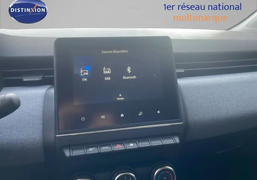 Vue rapprochée de l’écran tactile central et de la console de la Renault Clio blanche, avec commandes climatisation visibles.