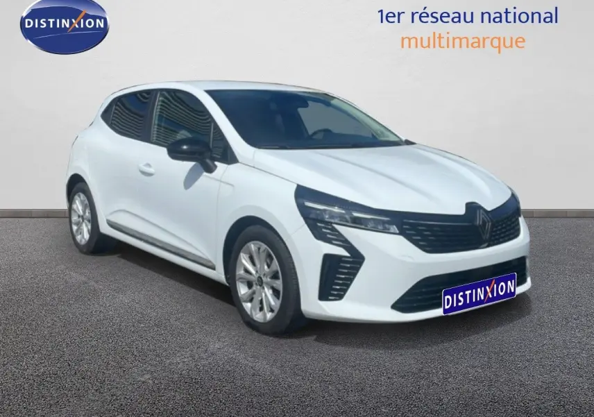 Renault Clio blanche vue 3/4 avant droit, avec calandre noire et jantes alliage argentées sur sol gris.