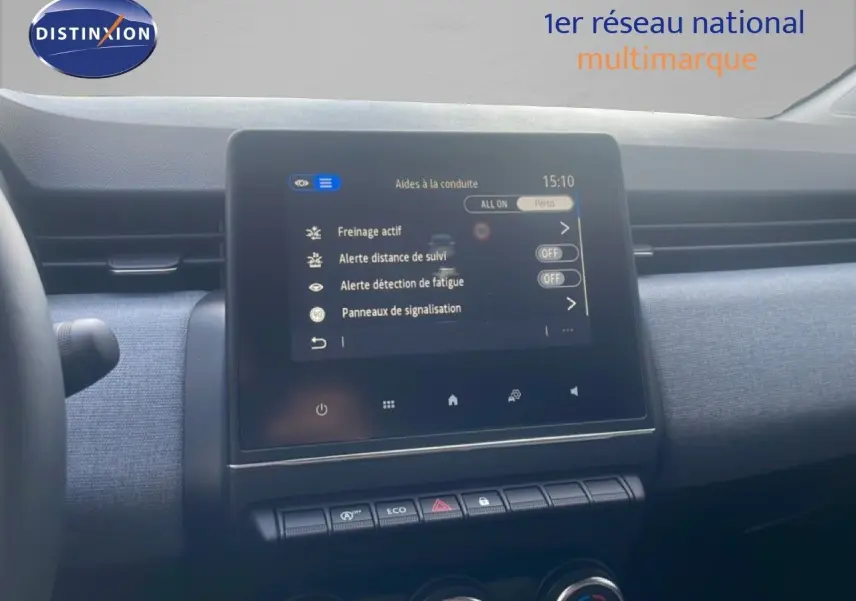 Vue rapprochée du tableau de bord de la Renault Clio blanche 2025, écran tactile affichant les aides à la conduite.