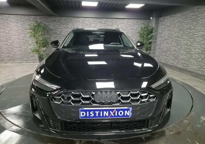 Vue avant d'une Audi A5 Avant noire 2025 avec calandre hexagonale et anneaux Audi gris anthracite.