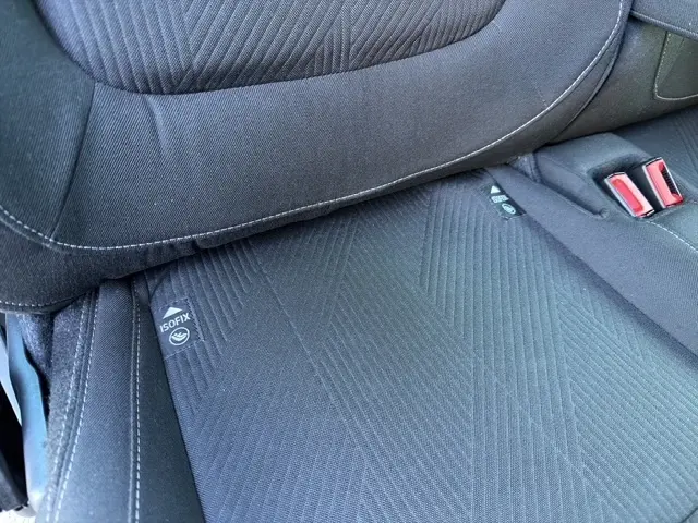 Détail du siège arrière gris foncé du Nissan Primastar 2025, montrant les fixations ISOFIX et les boucles de ceinture rouges.