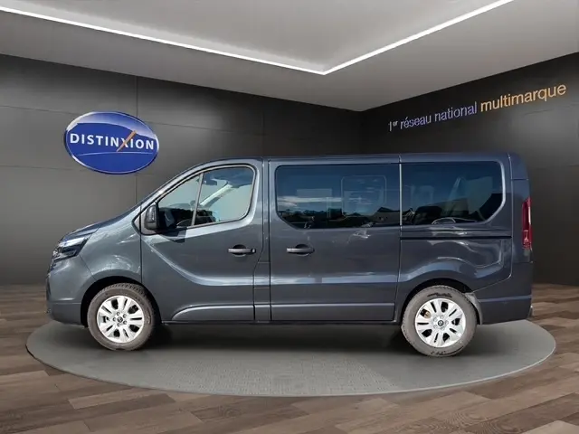 Vue de profil côté gauche d’un Nissan Primastar gris foncé avec vitres teintées et jantes acier blanches.