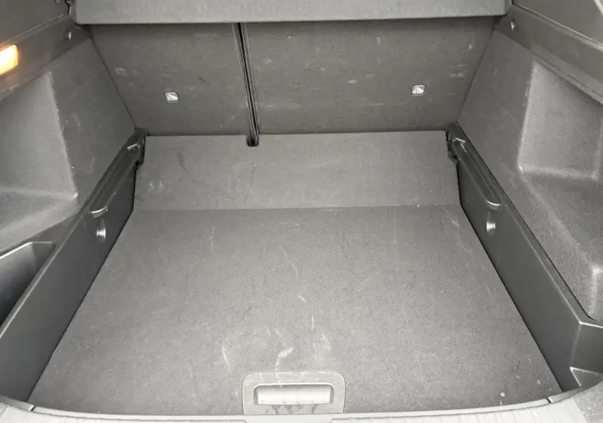 Coffre vide vu de l'intérieur, revêtement noir avec plancher plat et rangements latéraux intégrés.