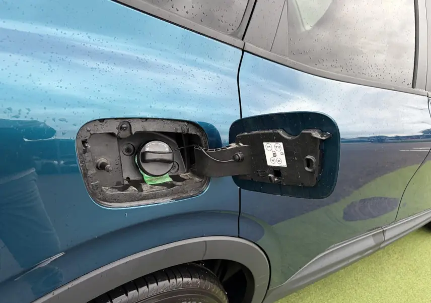 Vue rapprochée sur la trappe à carburant côté gauche d’un Renault Arkana bleu Zanzibar métallisé.
