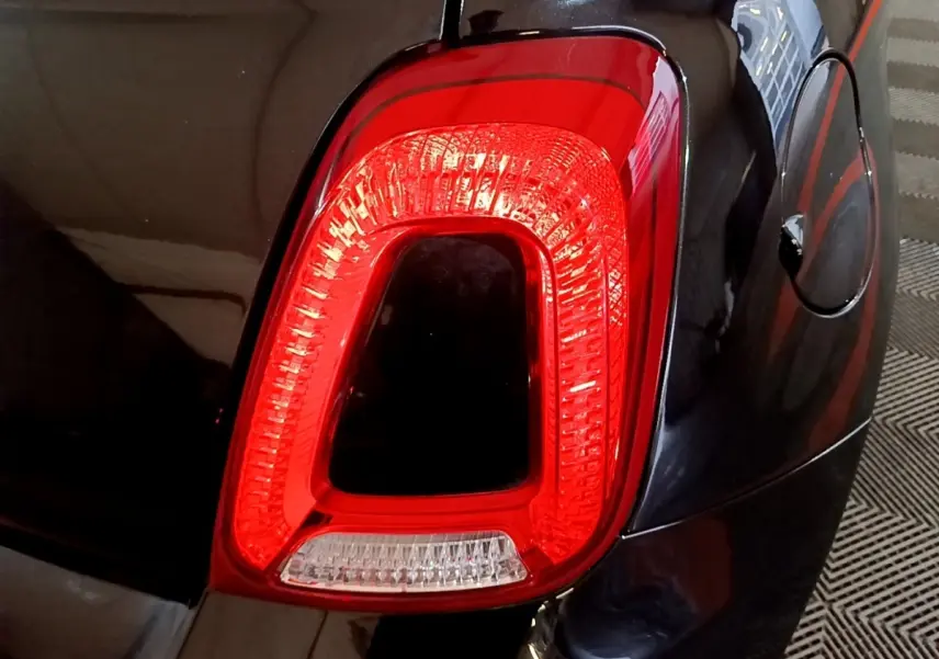Gros plan sur le feu arrière droit rouge de la FIAT 500 noire, avec la trappe à carburant visible à côté.