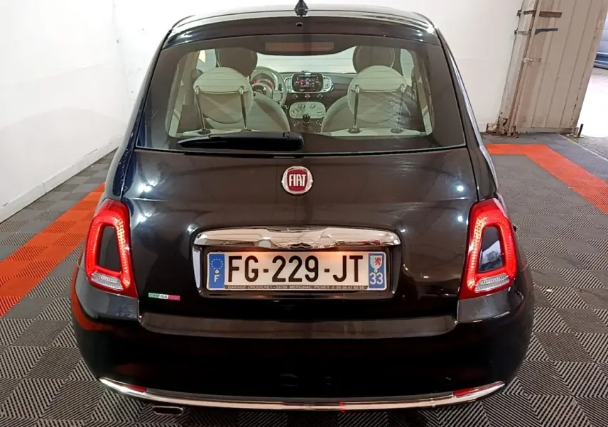 Vue arrière d'une FIAT 500 noire de 2019, avec feux arrière allumés et intérieur visible à travers la lunette arrière.