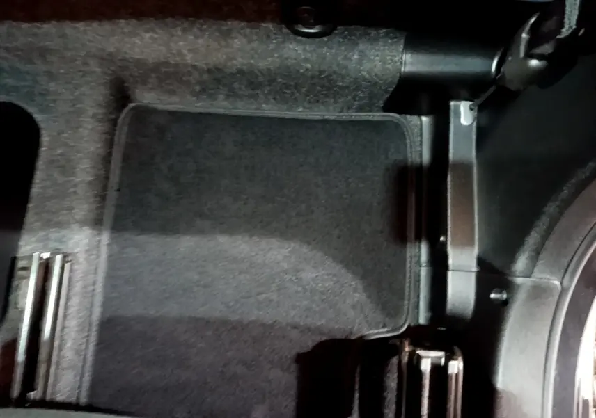 Vue du plancher côté conducteur de la Fiat 500 noire, montrant la moquette et les pédales en métal.