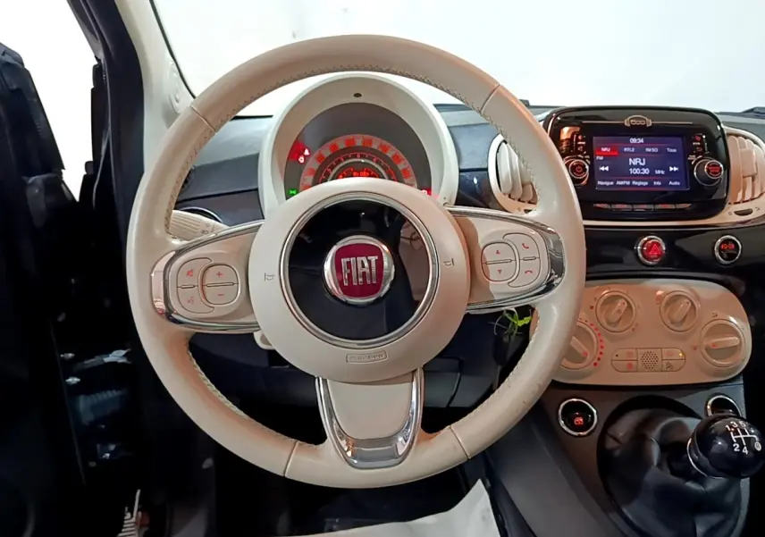 Vue intérieure centrée sur le volant beige de la Fiat 500 2019 avec tableau de bord et écran tactile noir.