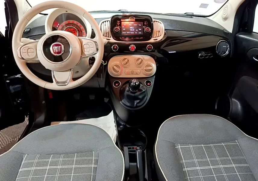 Vue intérieure avant de la Fiat 500 Lounge 2019, volant beige, tableau de bord noir brillant avec écran tactile central.