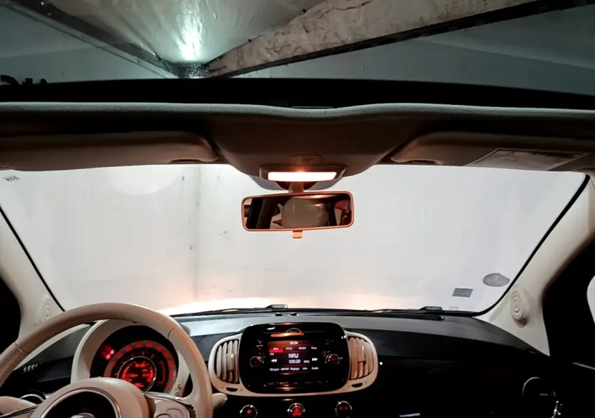 Vue intérieure avant du tableau de bord et volant beige de la FIAT 500 Lounge 2019 avec écran tactile central allumé.