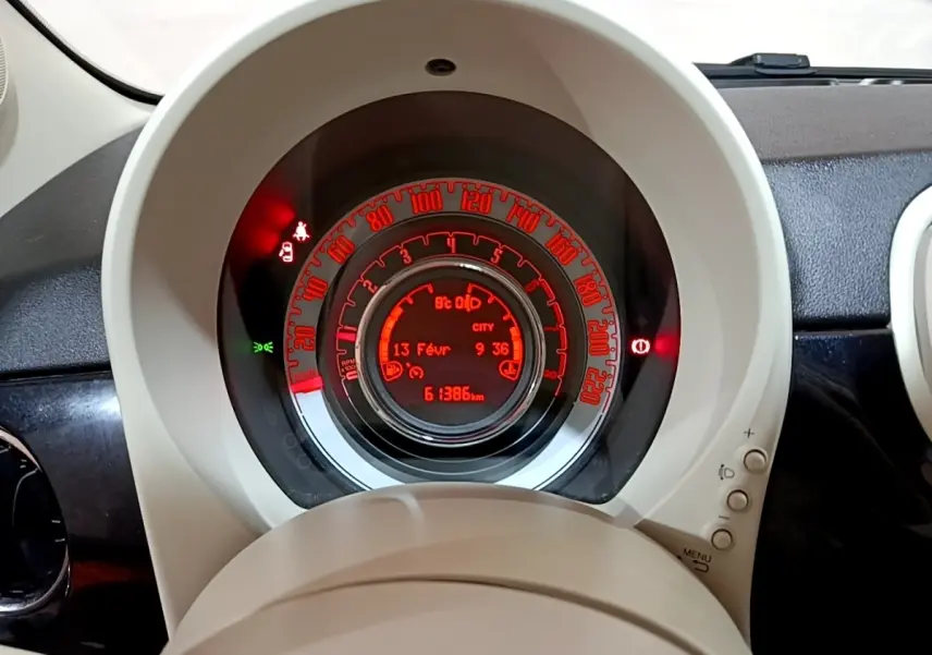 Vue rapprochée du tableau de bord central rougeoyant de la FIAT 500 Lounge 2019 avec affichage digital et compteur circulaire.