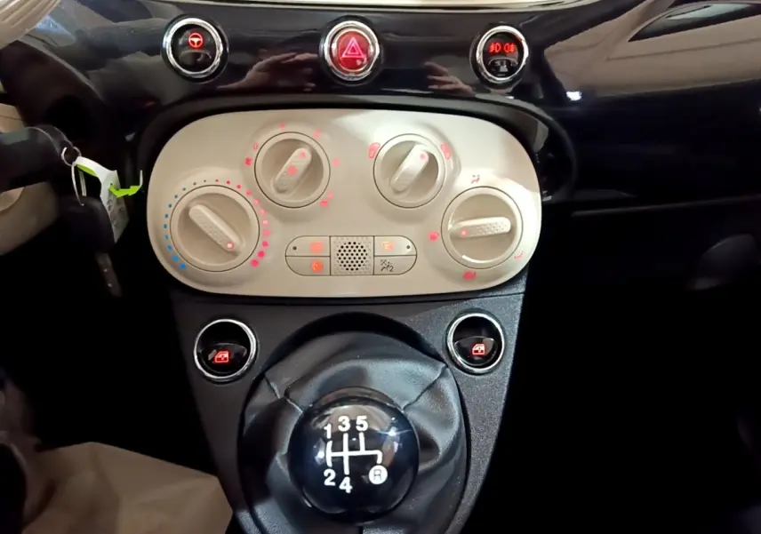 Gros plan sur la console centrale et levier de vitesses manuelle de la Fiat 500 noire, avec commandes de climatisation visibles.