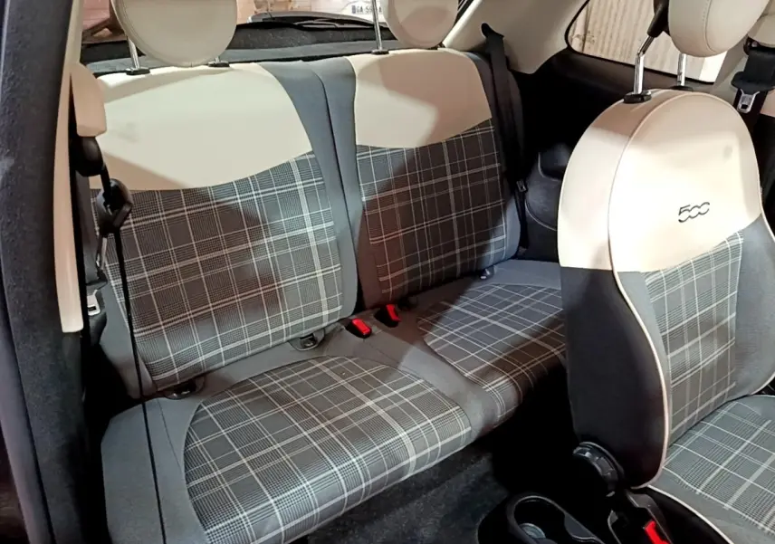 Vue intérieure sur les sièges arrière et avant d’une FIAT 500 noire, avec sellerie à motif écossais gris et beige.