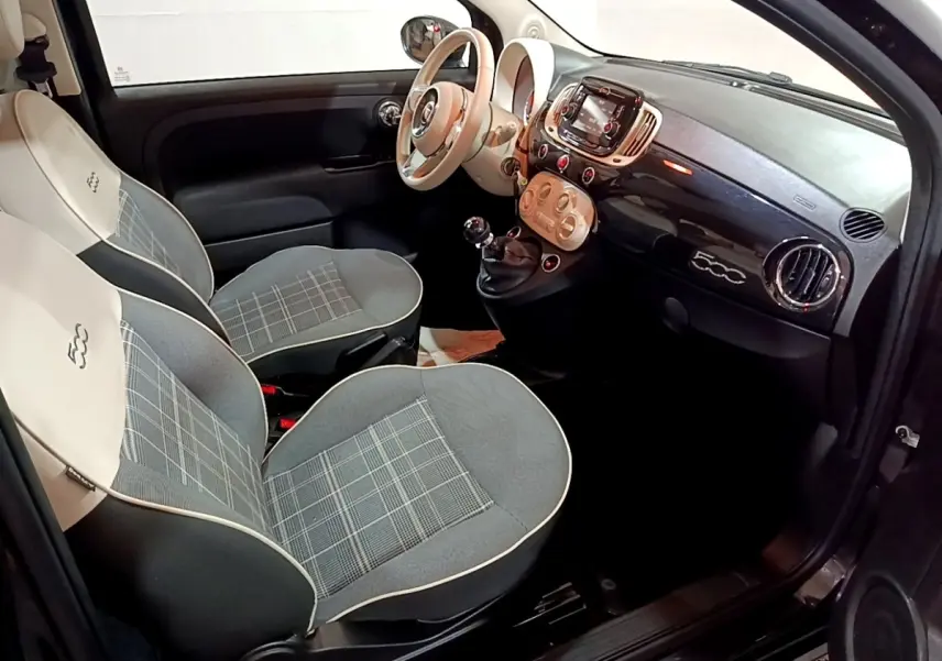 Vue intérieure côté conducteur de la Fiat 500 noire, montrant les sièges gris à motif à carreaux et le tableau de bord compact.