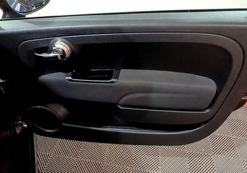 Vue rapprochée de la porte côté conducteur noire de la Fiat 500 Lounge avec poignée chrome et haut-parleur intégré.
