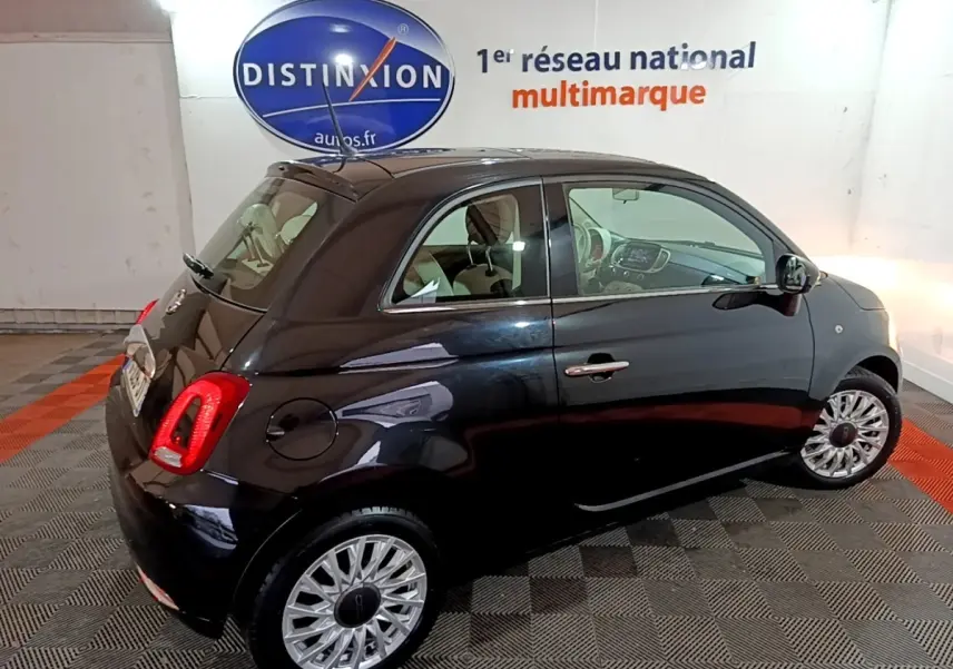Vue 3/4 arrière droite d'une FIAT 500 noire 2019 avec jantes alliage et intérieur beige visible en showroom.