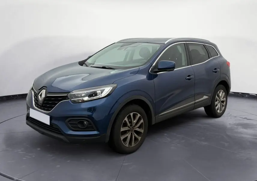 Renault Kadjar bleu cosmos en 3/4 avant droit, avec calandre noire et phares allumés sur parking extérieur.