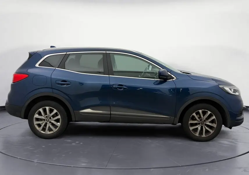 Vue 3/4 arrière droite d'un Renault Kadjar bleu cosmos 2020, avec feux arrière allumés et plaque d'immatriculation visible.
