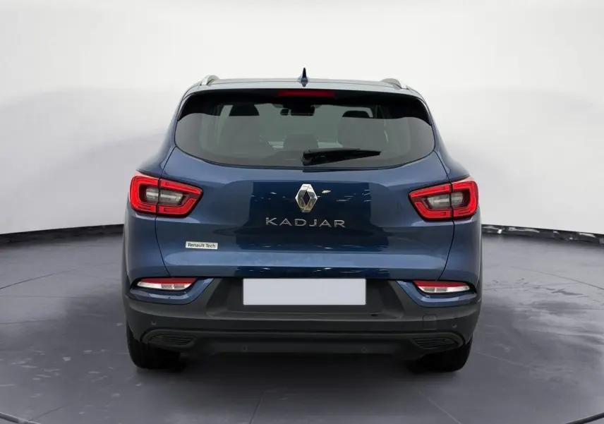 Vue 3/4 arrière droite d’un Renault Kadjar bleu cosmos 2020 garé sur un sol gravillonné en extérieur.
