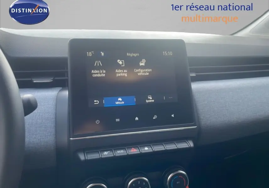 Vue intérieure centrée sur l’écran tactile et la console centrale d’une Renault Clio blanche, avec tableau de bord gris.