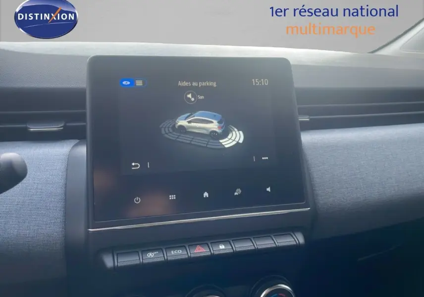 Vue rapprochée de l’écran tactile central du tableau de bord de la Renault Clio blanche 2025 avec aides au parking affichées.