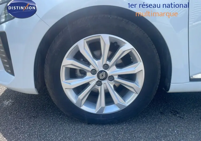 Gros plan sur la roue avant droite de la Renault Clio blanche 2025, mettant en valeur la jante alliage au design moderne.