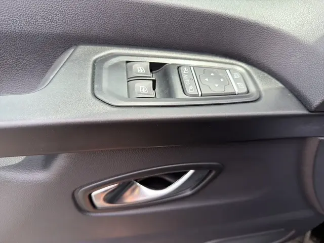 Détail des commandes de lève-vitres et réglage des rétroviseurs sur la porte intérieure noire côté conducteur du Nissan Primastar 2025.