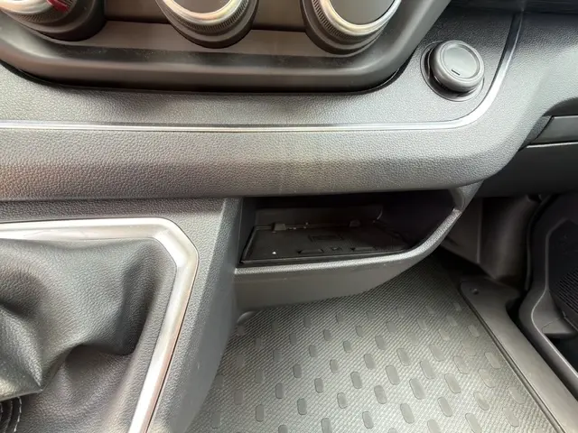 Détail de la console centrale noire du Nissan Primastar 2025, avec zone de recharge par induction et commande manuelle de boîte.