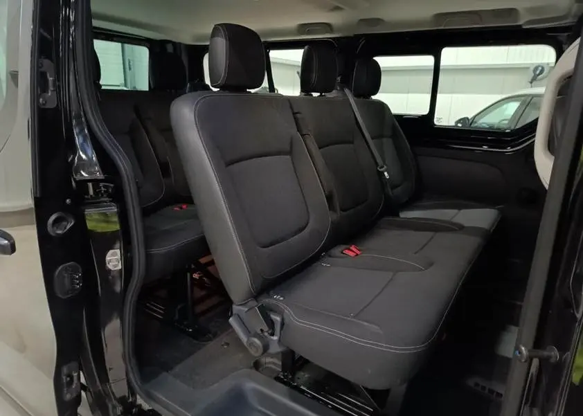 Vue intérieure côté droit du Nissan Primastar noir, montrant les sièges passagers en tissu avec ceintures de sécurité.
