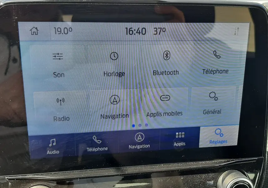 Écran tactile central du Ford Puma blanc 2022 montrant le menu des réglages avec commandes audio et navigation visibles.
