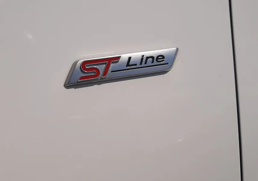 Gros plan sur l'emblème ST Line rouge et noir sur la carrosserie blanche d'une Ford Puma 2022.