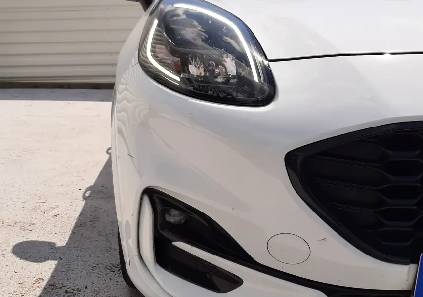 Gros plan sur l’avant droit blanc du Ford Puma 1.0 EcoBoost 125ch MHEV ST-Line avec phares LED et calandre noire.