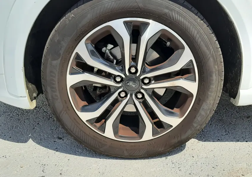 Gros plan sur la roue avant droite d'un Ford Puma blanc 2022 avec jante alliage bicolore et pneu Goodyear.