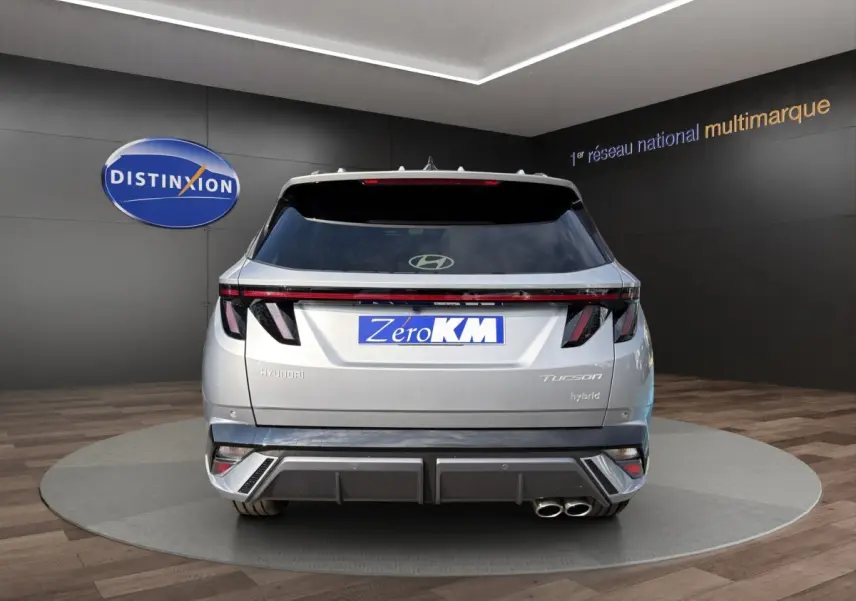 Vue arrière d’un Hyundai Tucson gris clair hybride 2026 avec feux LED et double sortie d’échappement chromée.