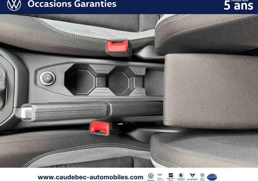 Vue plongeante sur la console centrale noire avec frein à main et deux ceintures rouges dans l'habitacle d'une Volkswagen Polo.