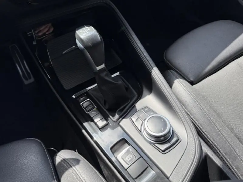 Gros plan sur la console centrale noire du BMW X2 xDrive25eA 2021, montrant levier de vitesses et commandes de navigation.