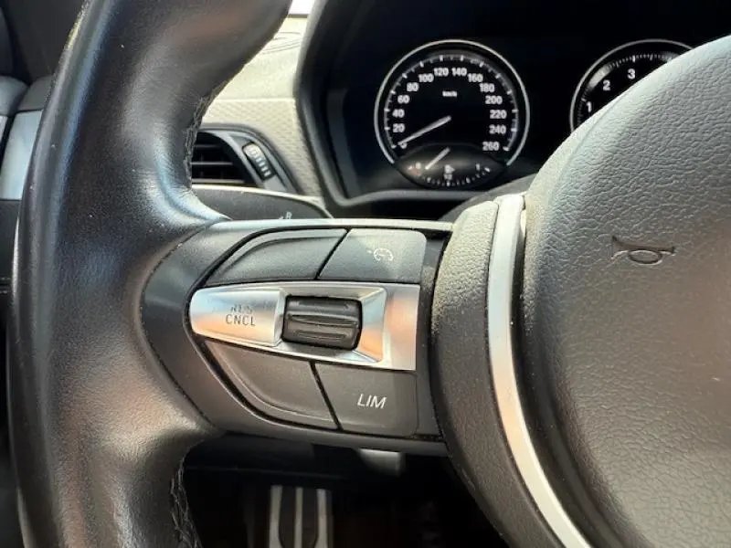 Gros plan sur le volant côté gauche d'une BMW X2 hybride rechargeable 2021, montrant les commandes de régulateur de vitesse.