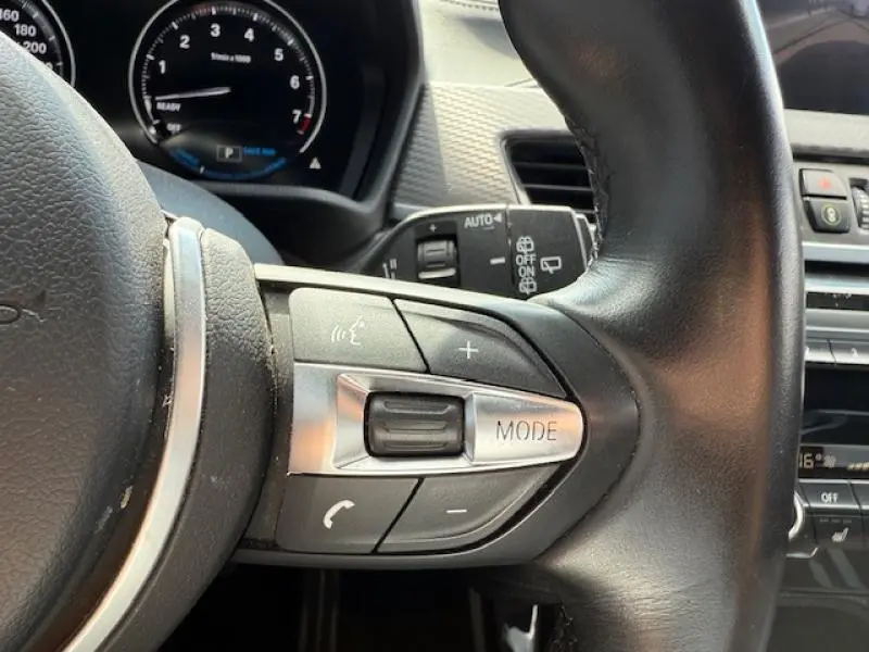 Gros plan sur les commandes au volant côté droit d'un BMW X2 hybride rechargeable 2021 en Galvanic Gold métallisé.