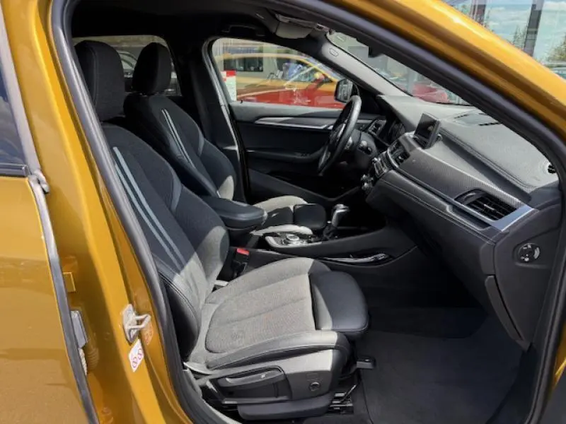 Intérieur côté conducteur d'un BMW X2 Galvanic Gold 2021, montrant sièges noirs et tableau de bord moderne.