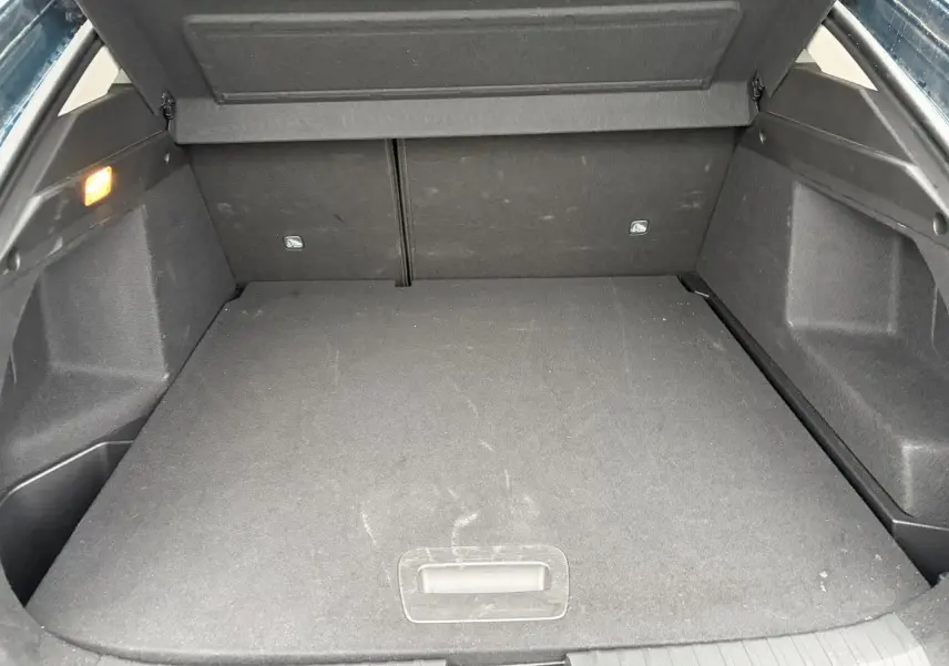 Coffre ouvert de Renault Arkana bleu Zanzibar, vue arrière montrant l'espace de chargement plat et éclairé.