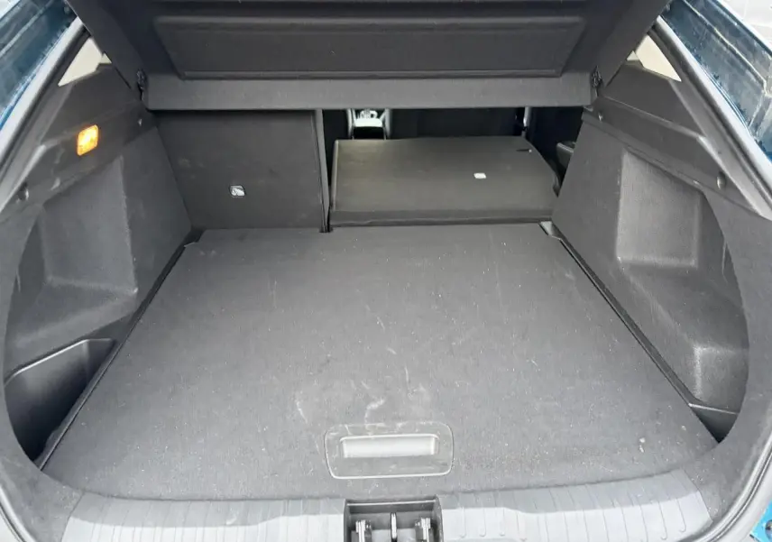 Coffre ouvert du Renault Arkana bleu Zanzibar, vue intérieure montrant le plancher plat et la banquette arrière rabattue.