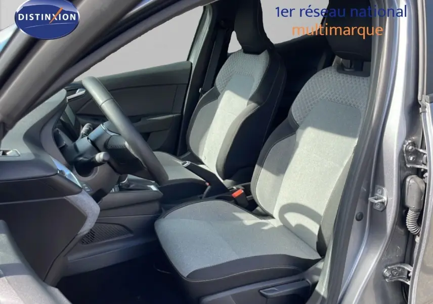 Vue intérieure côté conducteur de la Renault Clio gris schiste métal, sièges tissu bicolore et volant cuir multifonction.