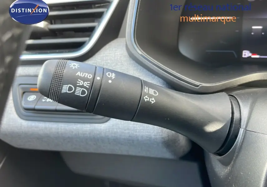 Gros plan sur la commande des phares et clignotants à gauche du volant dans l’habitacle gris d’une Renault Clio 2025.