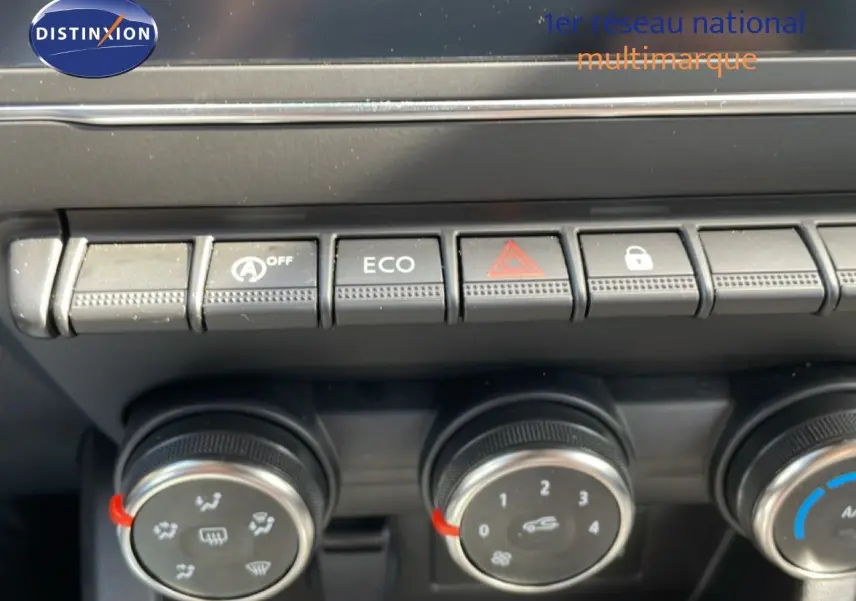 Gros plan sur les commandes de climatisation et boutons fonctionnels du tableau de bord d’une Renault Clio gris schiste.