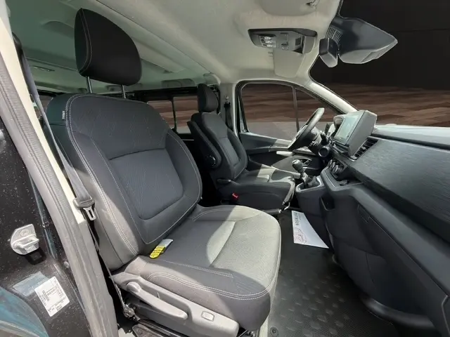 Vue intérieure côté conducteur du Nissan Primastar noir 2025, montrant les sièges avant et le tableau de bord moderne avec écran tactile.