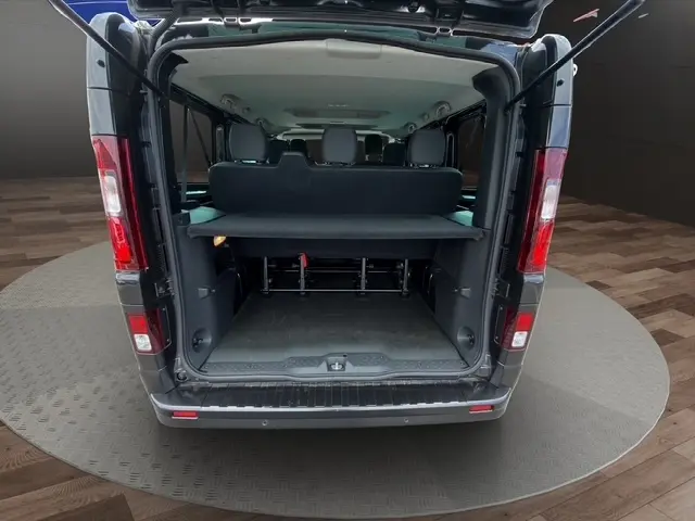 Vue arrière ouverte du Nissan Primastar noir 2025 montrant l'espace de chargement et les sièges arrière.