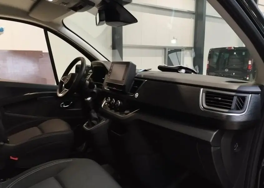 Intérieur côté conducteur du Nissan Primastar noir, vue sur tableau de bord avec écran tactile central et volant multifonctions.