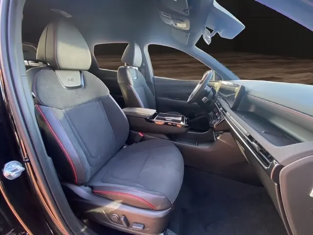 Vue intérieure côté conducteur du Hyundai Tucson 1.6 Hybrid N Line 2026 noir, sièges sport avec surpiqûres rouges et tableau de bord moderne.